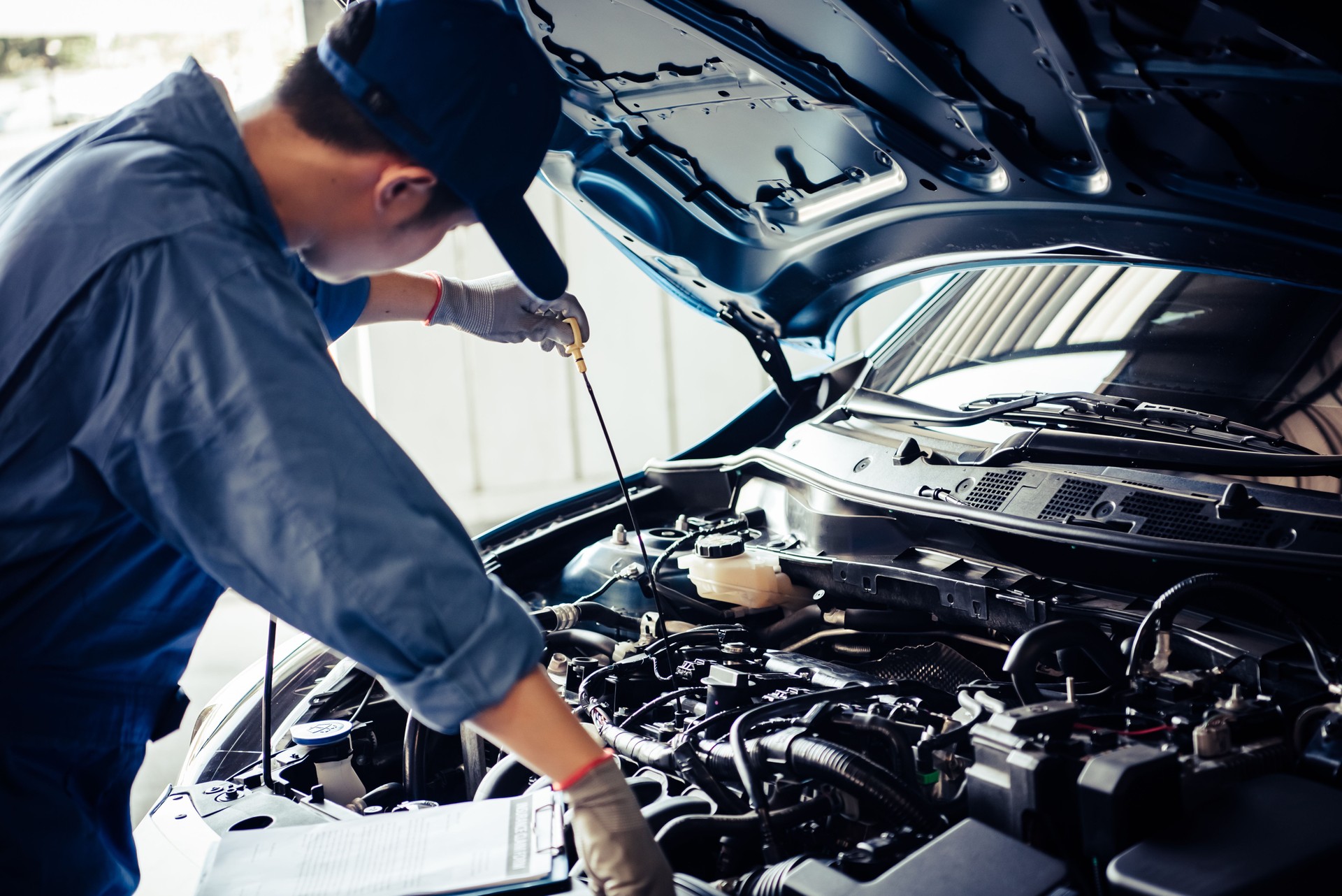 Car mechanic holding checking gear oil to maintenance vehicle by customer claim order in auto repair shop garage. Engine repair service. People occupation and business job. Automobile technician