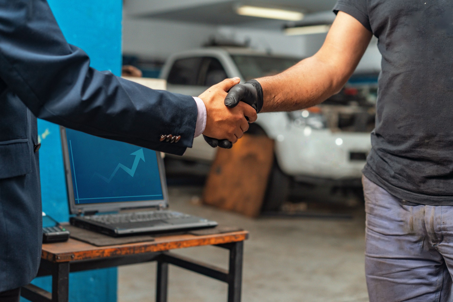 Close-up of auto mechanic worker and businessman client hands shaking hands during periodic car condition check.